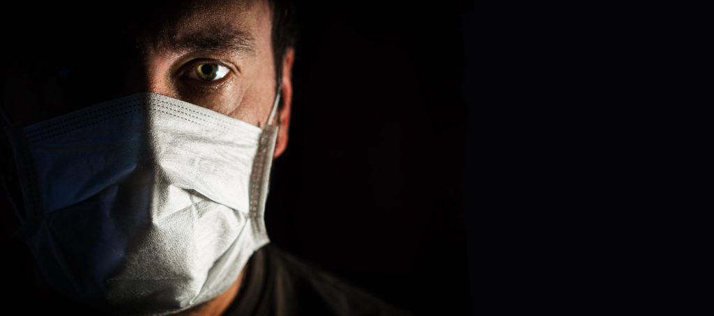 portrait of a man in a medical mask in a low key. a worldwide tragedy. COVID-19 virus pandemic warning.