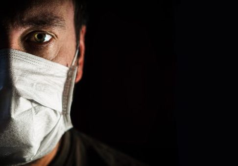 portrait of a man in a medical mask in a low key. a worldwide tragedy. COVID-19 virus pandemic warning.